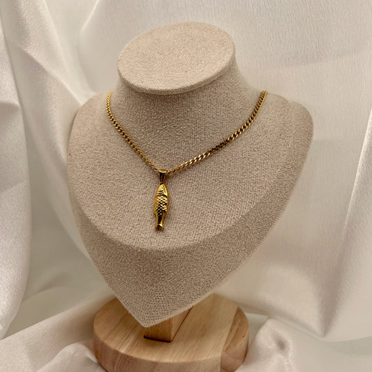 Gold necklace with a fish pendant on a beige jewelry display