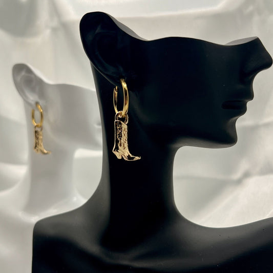 Gold earrings displayed on a black mannequin bust against a white fabric background