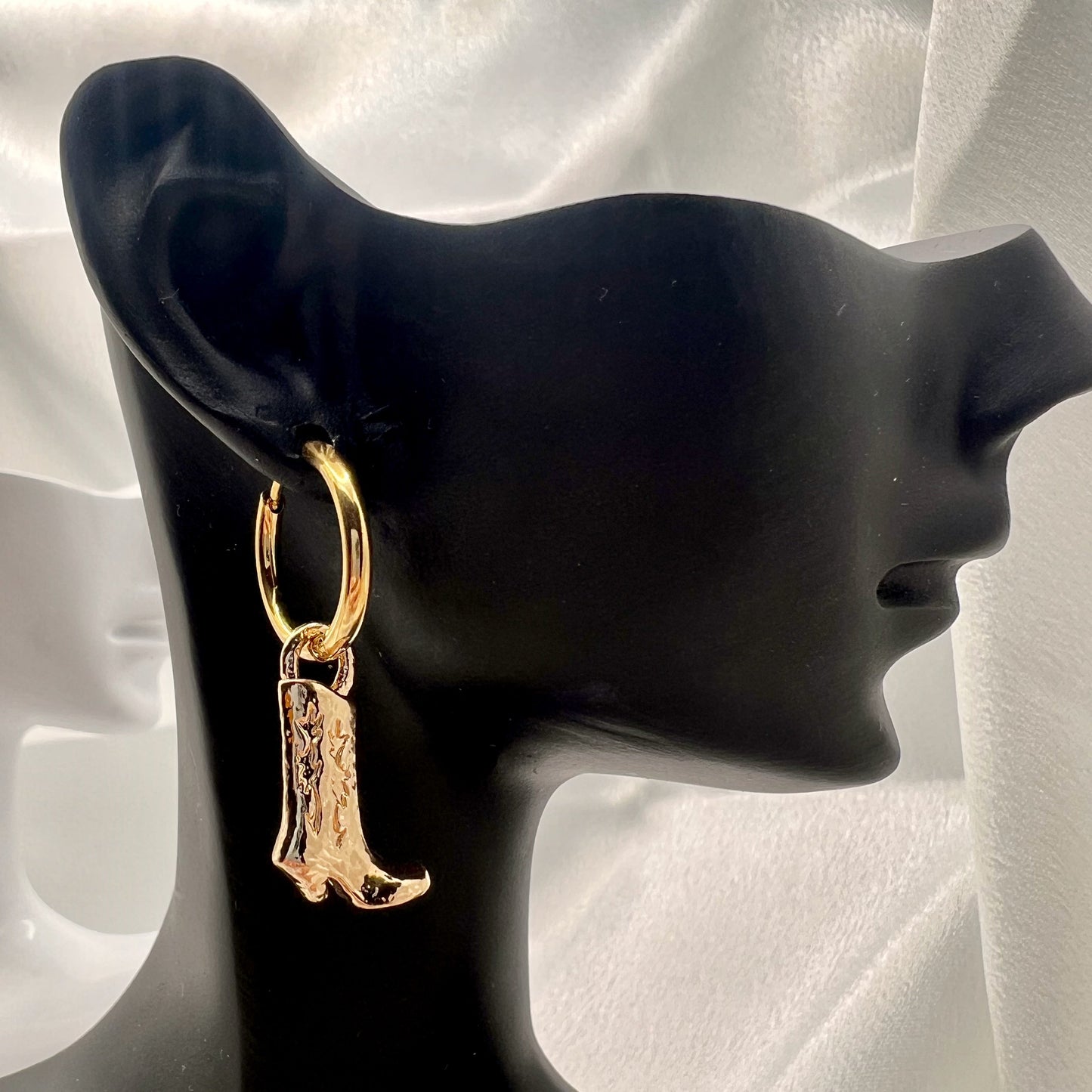 Gold cowboy boot earring on a black mannequin ear
