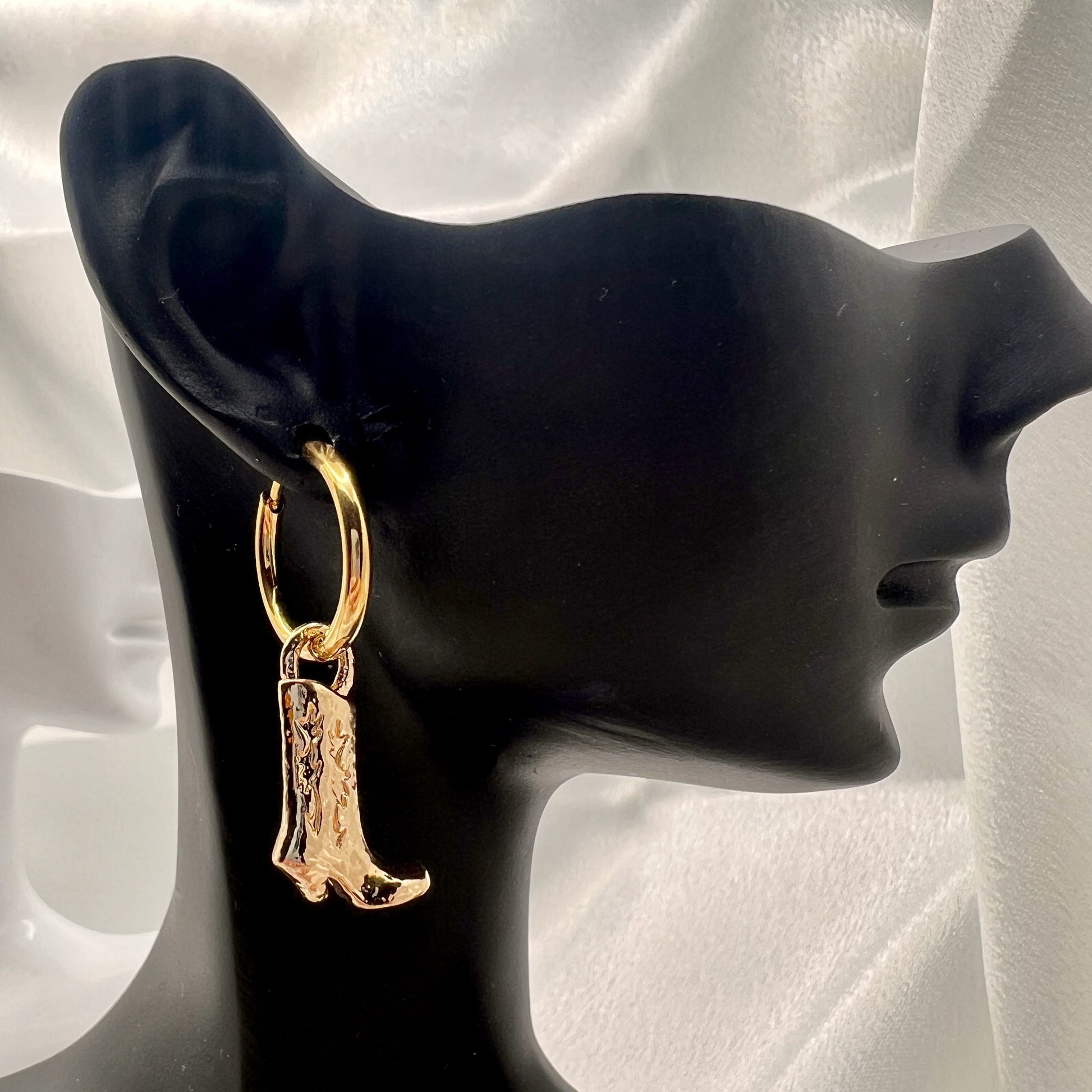 Gold cowboy boot earring on a black mannequin ear