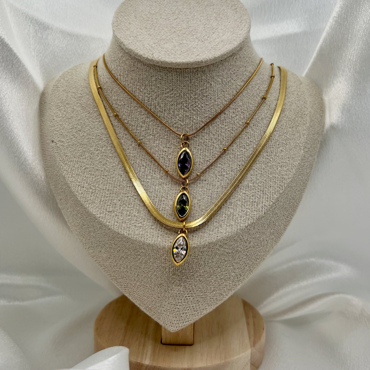 Gold necklace with gemstones on a mannequin bust against a white fabric background